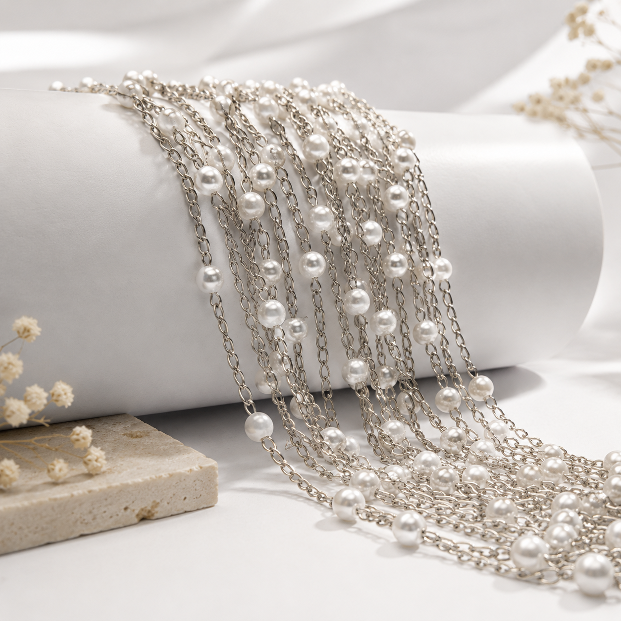 Correntes prateadas com pérolas sobre tecido branco