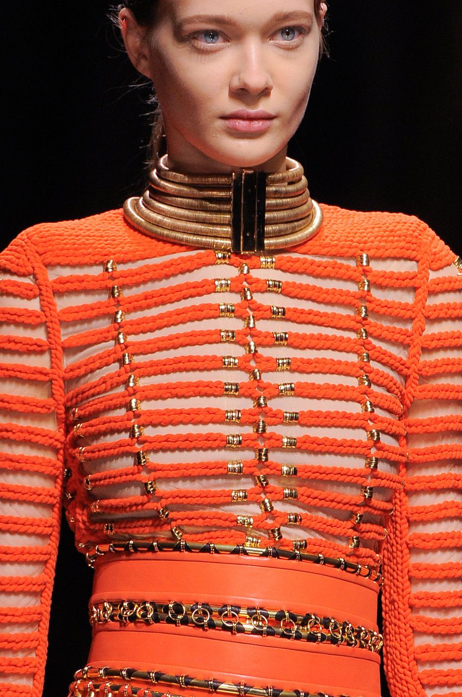 Look de confecção laranja com aplicações metálicas douradas